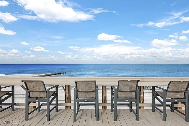 wooden terrace featuring a beach view and a water view