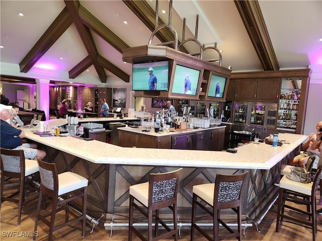 bar with light stone countertops, wood-type flooring, lofted ceiling with beams, and dark brown cabinets