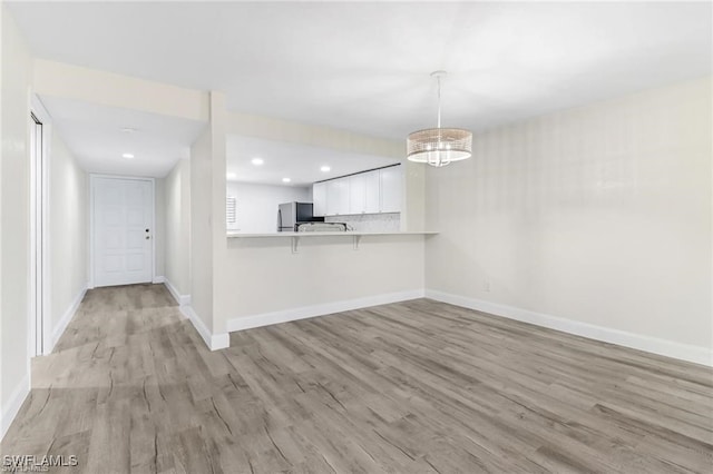 interior space featuring white cabinets, light wood-type flooring, and kitchen peninsula