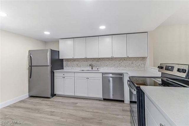 kitchen featuring sink, stainless steel appliances, tasteful backsplash, white cabinets, and light wood-type flooring