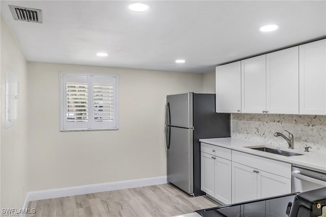 kitchen with appliances with stainless steel finishes, light hardwood / wood-style flooring, white cabinetry, and sink