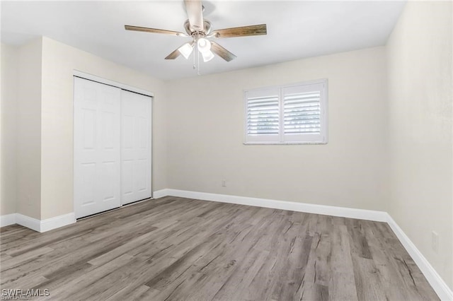 unfurnished bedroom with light hardwood / wood-style floors, a closet, and ceiling fan