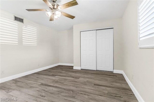 unfurnished bedroom featuring hardwood / wood-style flooring, ceiling fan, and a closet