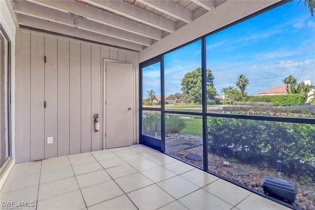 unfurnished sunroom featuring beam ceiling