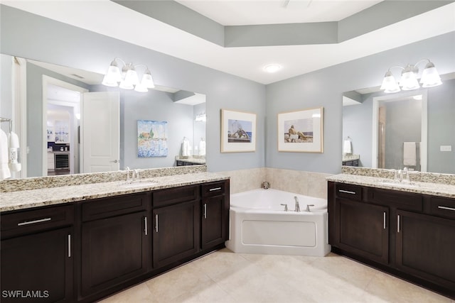 bathroom with vanity, tile patterned floors, a tub, and a raised ceiling