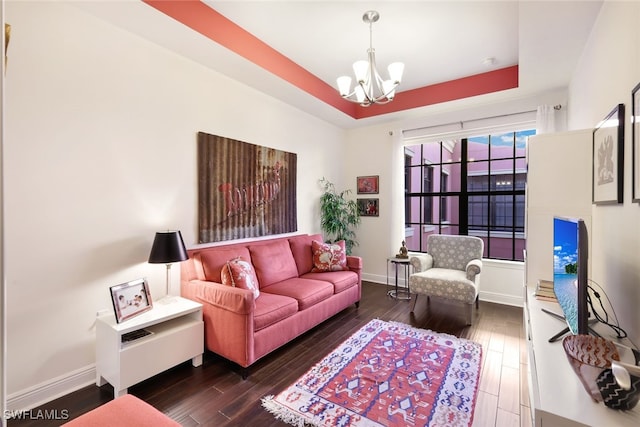 living room featuring a notable chandelier, a tray ceiling, and dark hardwood / wood-style floors