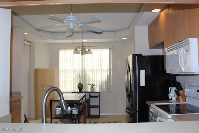 kitchen featuring a tray ceiling, light tile patterned floors, ceiling fan with notable chandelier, and white appliances