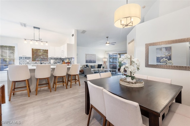 dining room featuring ceiling fan with notable chandelier, a wealth of natural light, and light hardwood / wood-style flooring