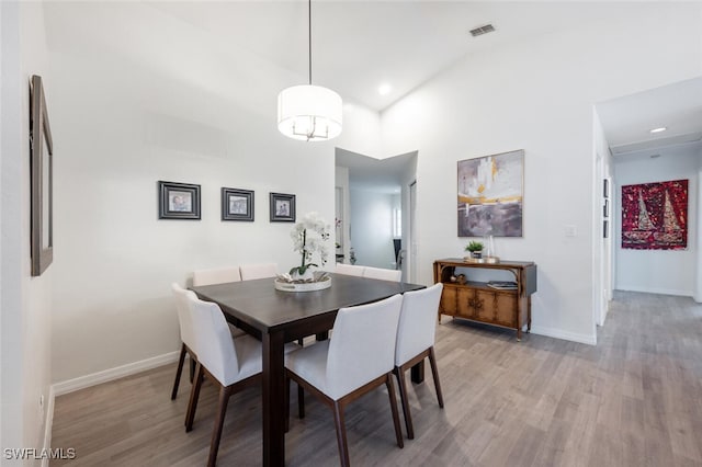 dining space with light hardwood / wood-style floors and high vaulted ceiling