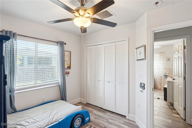 bedroom with multiple windows, light wood-type flooring, ceiling fan, and a closet