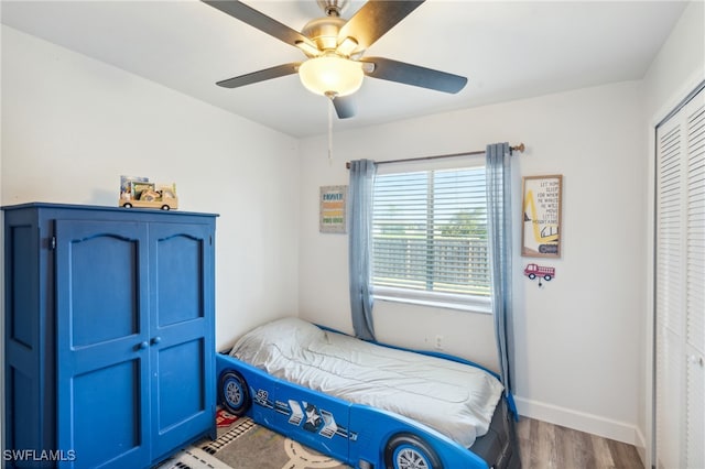 bedroom with dark wood-type flooring, ceiling fan, and a closet