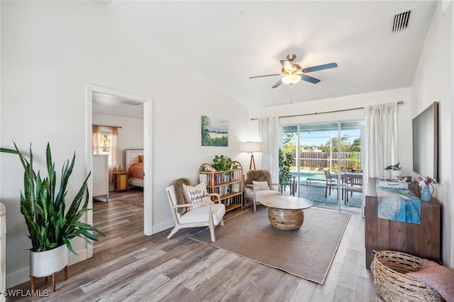 sitting room with ceiling fan, lofted ceiling, wood finished floors, visible vents, and baseboards