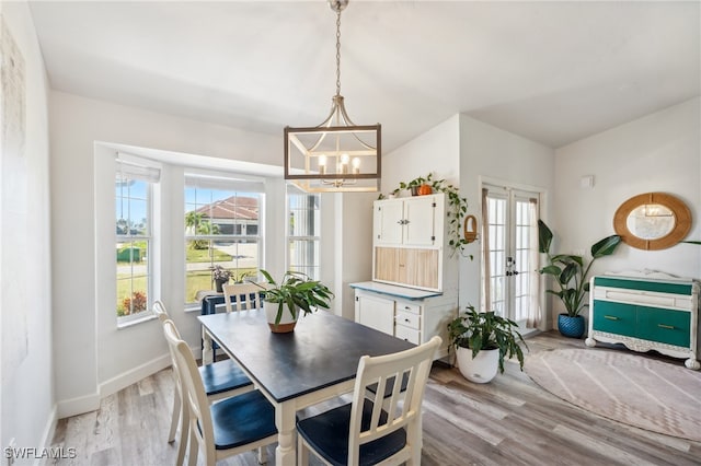 dining room with french doors, light hardwood / wood-style flooring, and a notable chandelier