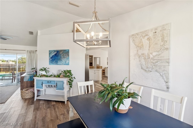 dining room with vaulted ceiling, hardwood / wood-style floors, and a notable chandelier