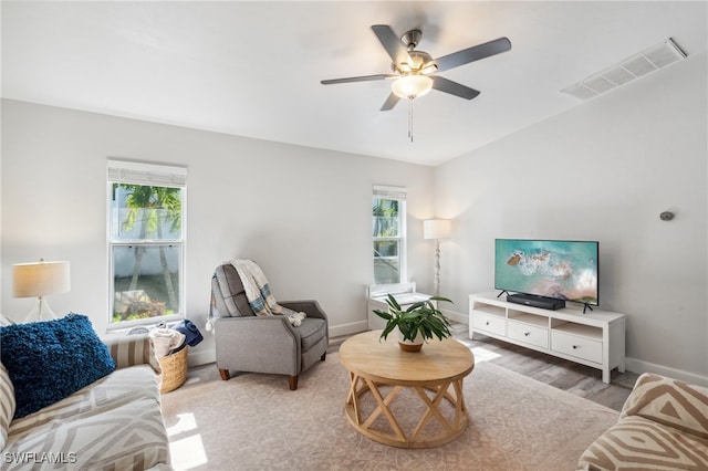 living room with a wealth of natural light, light hardwood / wood-style floors, and ceiling fan