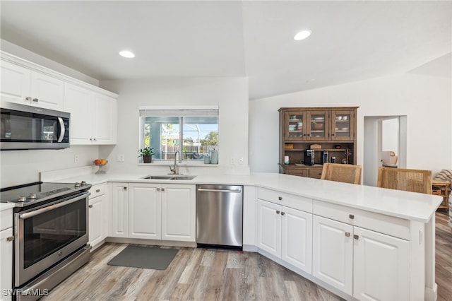 kitchen with appliances with stainless steel finishes, sink, white cabinets, and kitchen peninsula