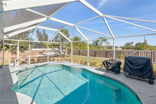 view of swimming pool with a grill, a patio area, and glass enclosure