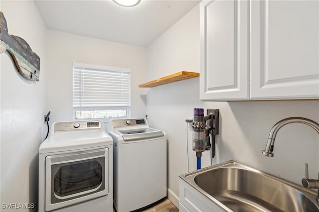 clothes washing area with cabinets, washing machine and dryer, and sink