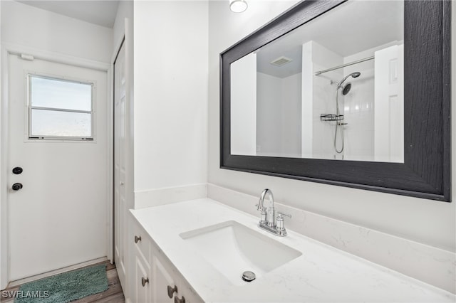 bathroom with vanity and a tile shower