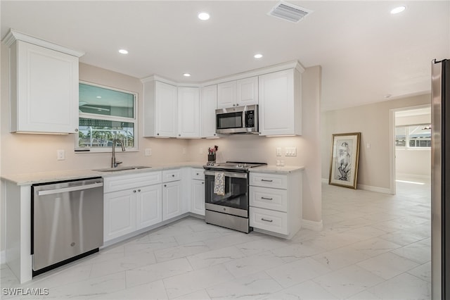 kitchen with a healthy amount of sunlight, white cabinetry, sink, and appliances with stainless steel finishes