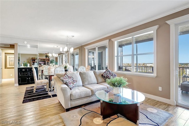 living room with ornamental molding, an inviting chandelier, and light hardwood / wood-style flooring