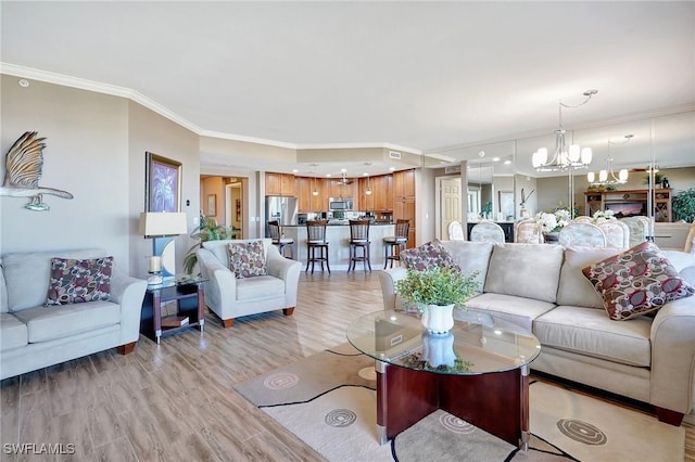 living room featuring a notable chandelier, ornamental molding, and light wood-type flooring