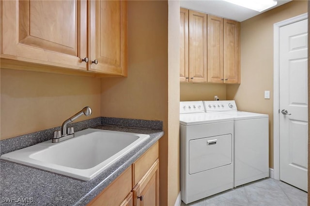 clothes washing area with sink, washer and clothes dryer, cabinets, and light tile patterned flooring