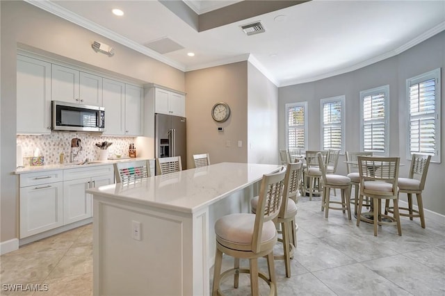 kitchen with white cabinetry, a kitchen island, a kitchen breakfast bar, and appliances with stainless steel finishes