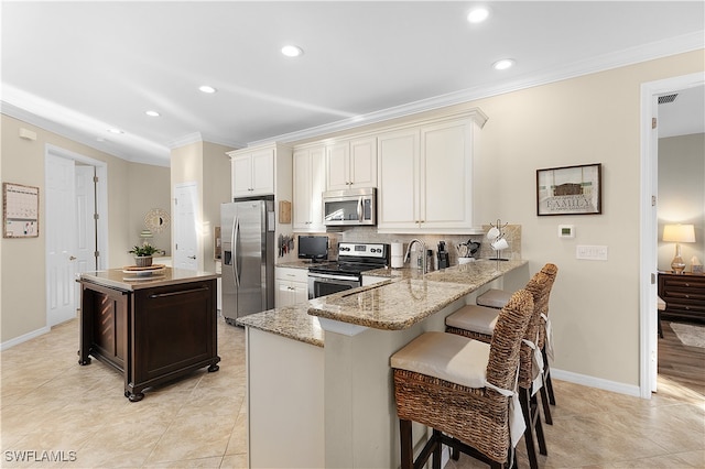 kitchen featuring tasteful backsplash, light stone counters, kitchen peninsula, a breakfast bar area, and appliances with stainless steel finishes