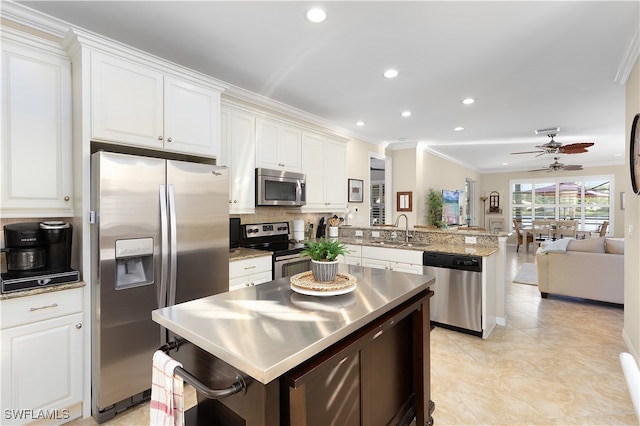 kitchen with kitchen peninsula, stainless steel appliances, ceiling fan, sink, and white cabinets