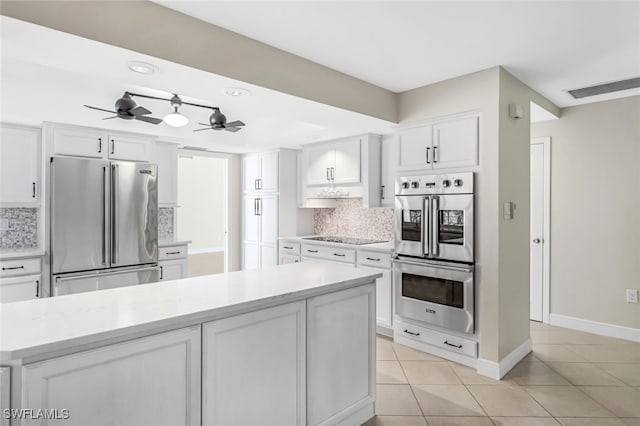 kitchen featuring light tile patterned floors, white cabinetry, appliances with stainless steel finishes, and tasteful backsplash