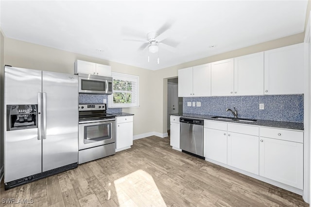 kitchen with appliances with stainless steel finishes, tasteful backsplash, sink, white cabinets, and light hardwood / wood-style floors