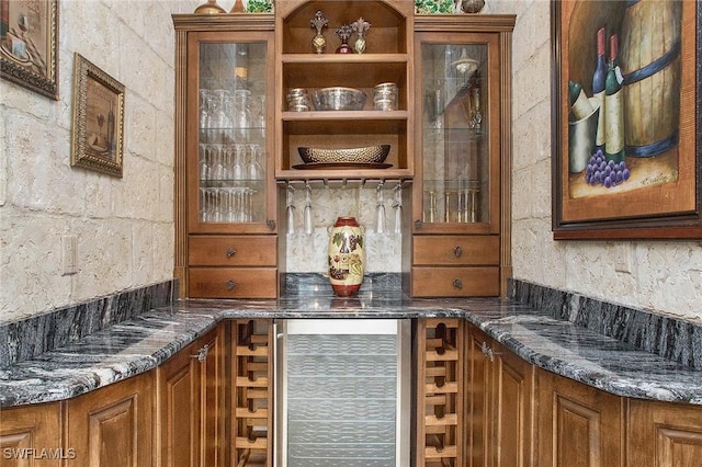 bar with wine cooler and dark stone counters