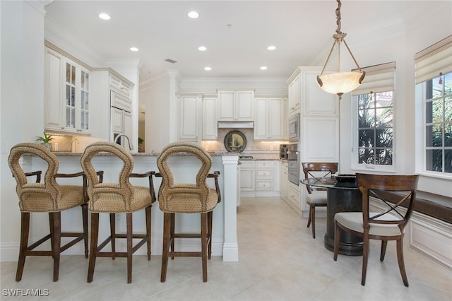 kitchen featuring stainless steel appliances, tasteful backsplash, hanging light fixtures, light stone countertops, and white cabinets