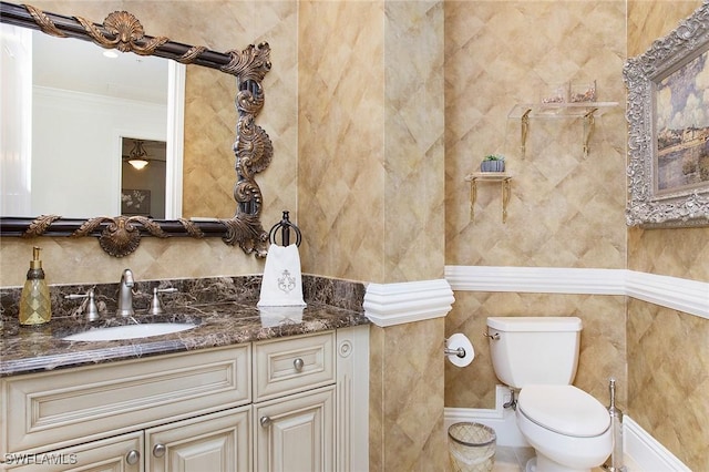 bathroom with toilet, vanity, and ornamental molding