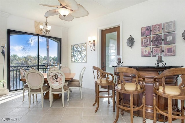 dining area featuring ceiling fan with notable chandelier, indoor bar, and light tile patterned flooring