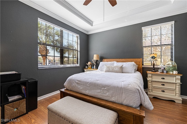 bedroom with a tray ceiling, ceiling fan, wood-type flooring, and ornamental molding