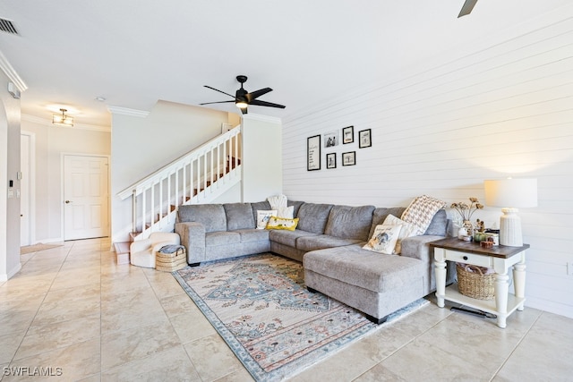 tiled living room with ceiling fan, crown molding, and wood walls