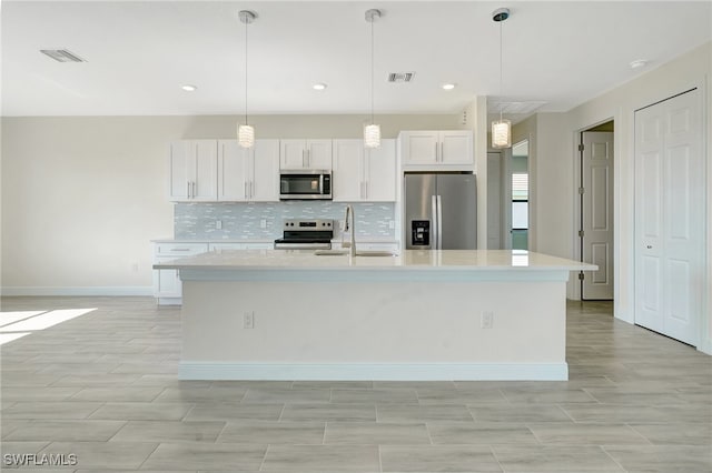 kitchen with sink, white cabinets, stainless steel appliances, and a center island with sink