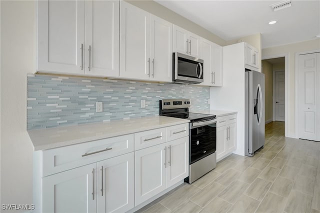 kitchen featuring decorative backsplash, light stone counters, white cabinetry, and stainless steel appliances