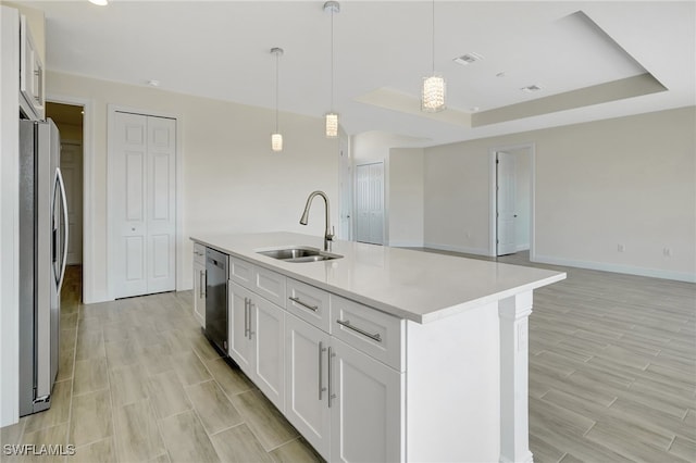 kitchen featuring white cabinets, appliances with stainless steel finishes, a kitchen island with sink, and sink