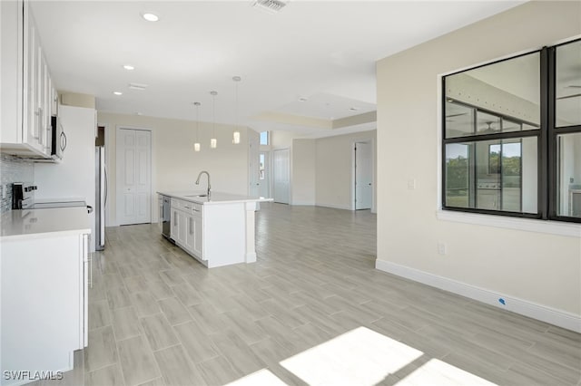 kitchen with pendant lighting, an island with sink, light hardwood / wood-style floors, white cabinetry, and stainless steel appliances