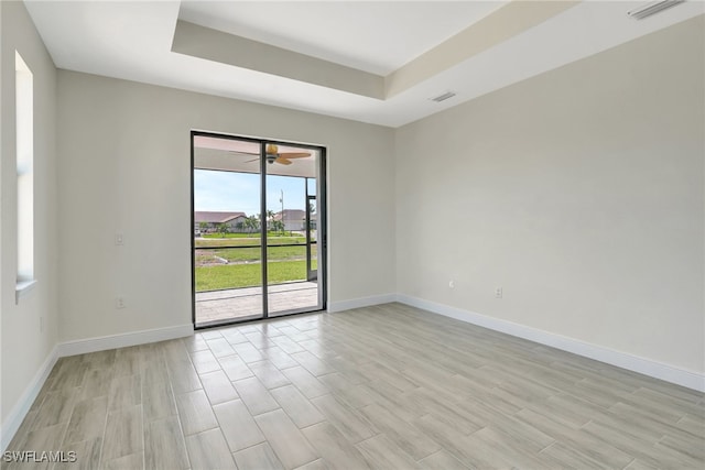 unfurnished room featuring ceiling fan, a raised ceiling, and light hardwood / wood-style flooring