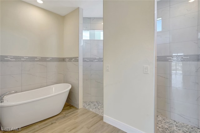 bathroom with hardwood / wood-style floors, plus walk in shower, and tile walls