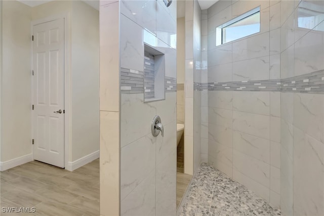 bathroom with a tile shower and wood-type flooring