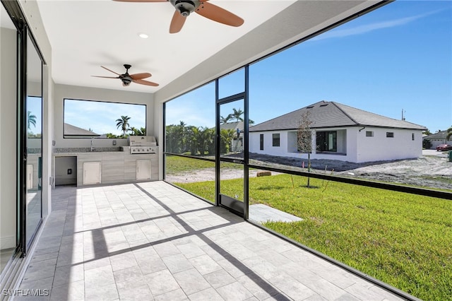 unfurnished sunroom featuring ceiling fan and sink