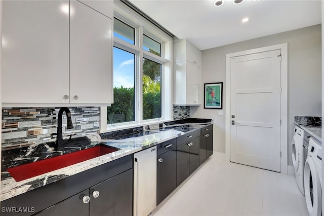 kitchen featuring backsplash, stainless steel dishwasher, sink, separate washer and dryer, and white cabinets