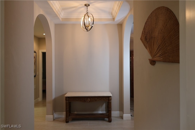 hall featuring a raised ceiling and an inviting chandelier