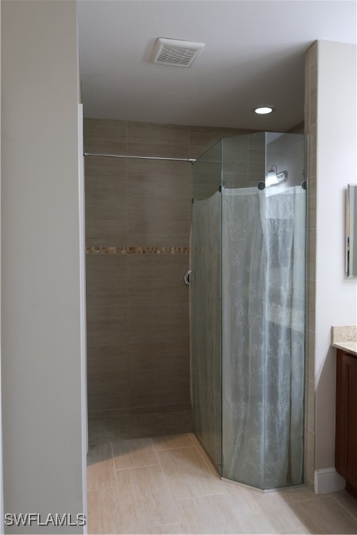 bathroom with tile patterned flooring, vanity, and tiled shower