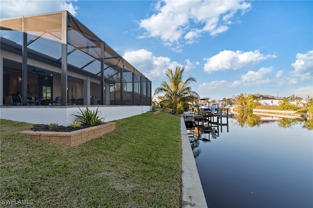 view of dock featuring a water view, a lanai, and a yard